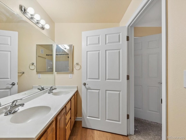 bathroom with double vanity, wood finished floors, and a sink