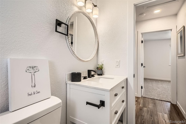 17979 E Oxford Pl, Aurora, CO 80013 - half bath featuring wood finished floors, vanity, toilet, and a textured wall