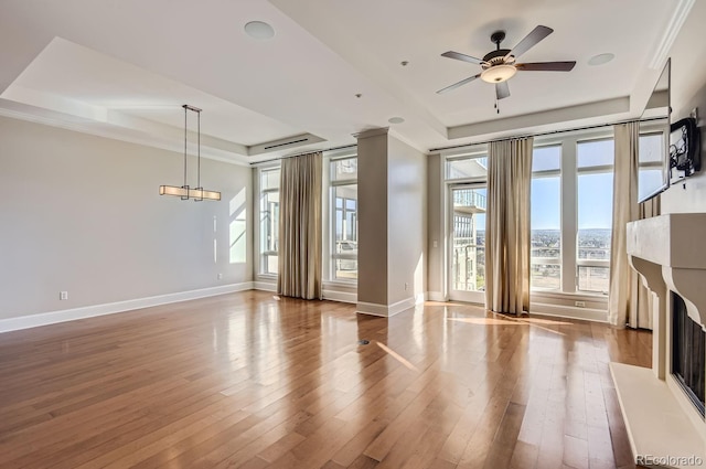 unfurnished living room with a tray ceiling, hardwood / wood-style flooring, and plenty of natural light