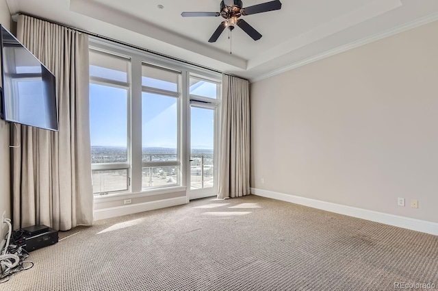 empty room featuring carpet floors, a tray ceiling, crown molding, and ceiling fan