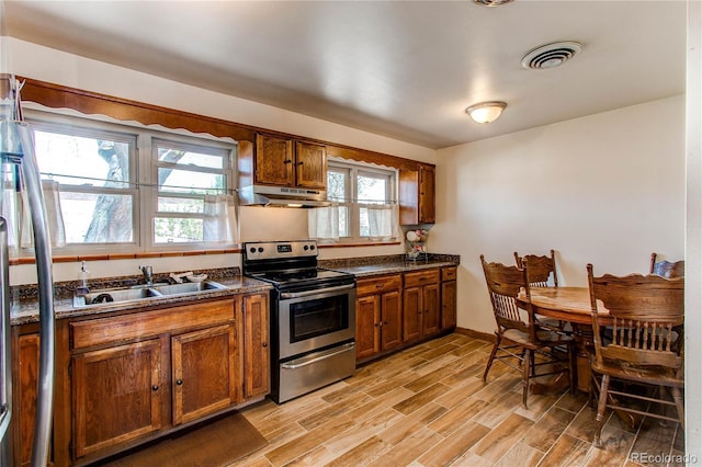 2785 Skyline Dr, Westminster, CO 80030 - kitchen with appliances with stainless steel finishes, brown cabinetry, a sink, under cabinet range hood, and light wood-style floors