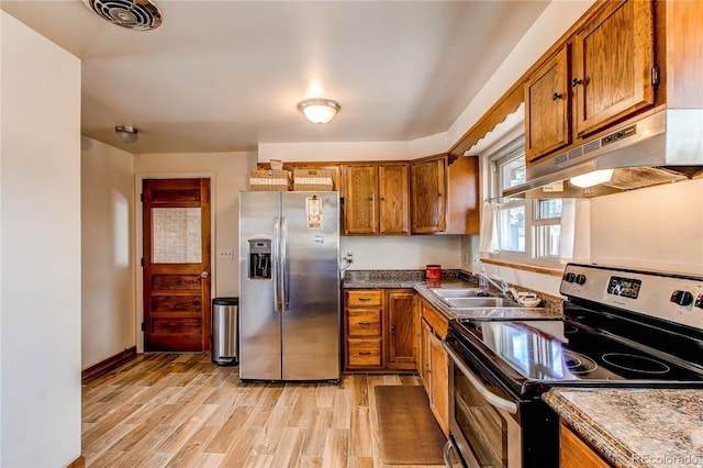 2785 Skyline Dr, Westminster, CO 80030 - kitchen featuring stainless steel appliances, under cabinet range hood, brown cabinetry, light wood-type flooring, and dark countertops