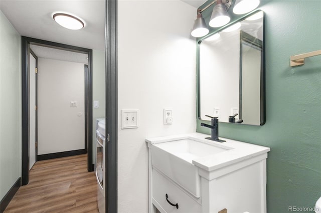 bathroom featuring washer and dryer, baseboards, wood finished floors, and vanity