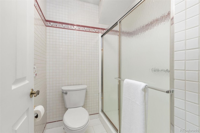 full bath with tile patterned flooring, tile walls, toilet, and a stall shower