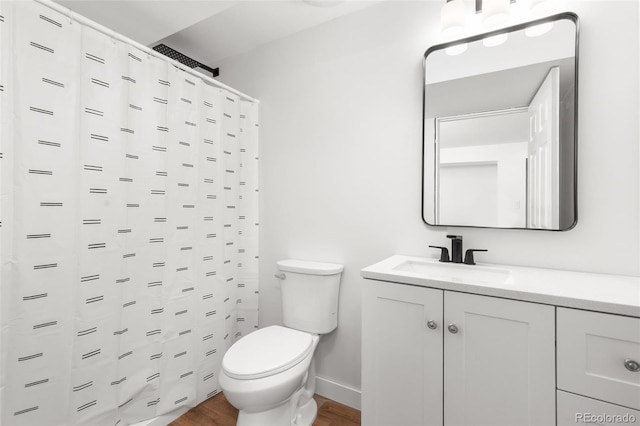 bathroom with toilet, curtained shower, wood finished floors, baseboards, and vanity