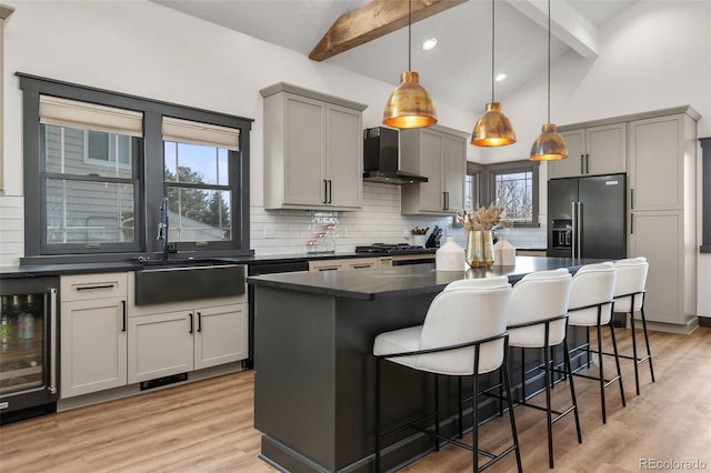 kitchen featuring high quality fridge, beverage cooler, gray cabinets, and wall chimney range hood