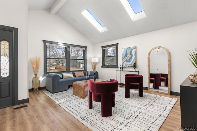 living room featuring beam ceiling, high vaulted ceiling, baseboards, and wood finished floors