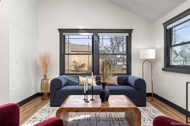 living room with vaulted ceiling, wood finished floors, and baseboards