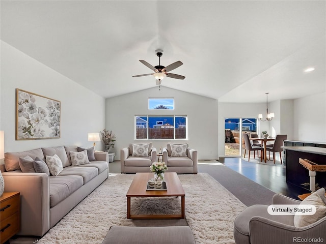 living room featuring vaulted ceiling, wood-type flooring, and ceiling fan with notable chandelier