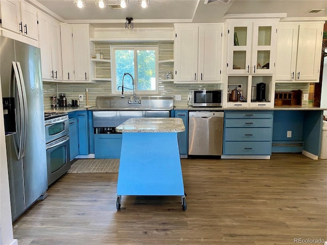 kitchen featuring a kitchen island, blue cabinets, wood-type flooring, appliances with stainless steel finishes, and white cabinetry