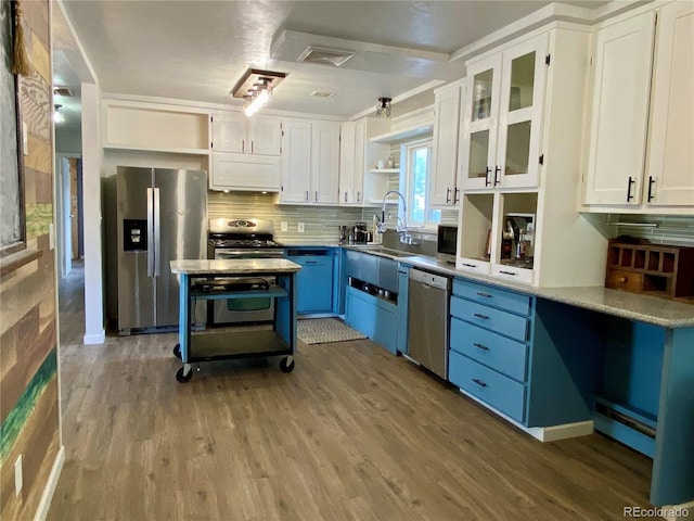 kitchen with wood-type flooring, stainless steel appliances, sink, and blue cabinetry