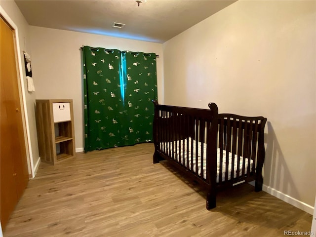 bedroom with a nursery area and light wood-type flooring