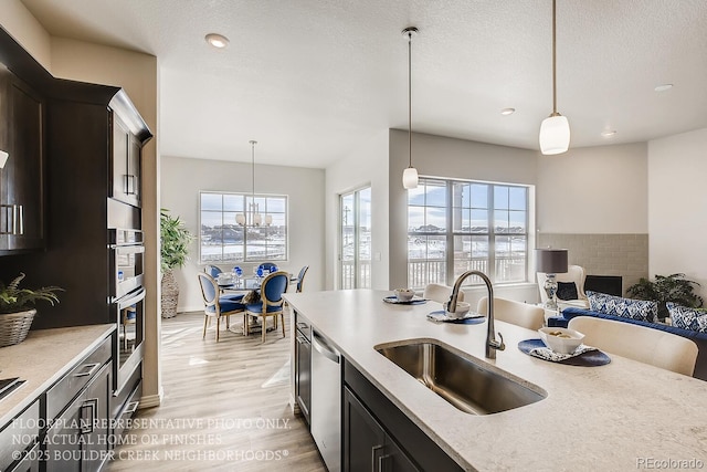 917 W 129th Pl, Denver, CO 80234 - kitchen with a sink, dishwasher, light wood finished floors, pendant lighting, and recessed lighting