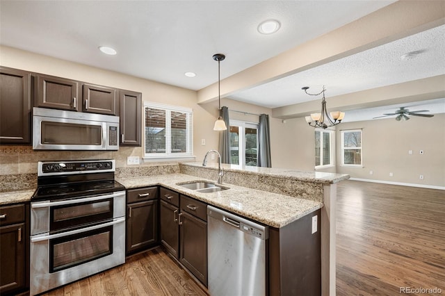 kitchen with sink, decorative light fixtures, stainless steel appliances, and kitchen peninsula