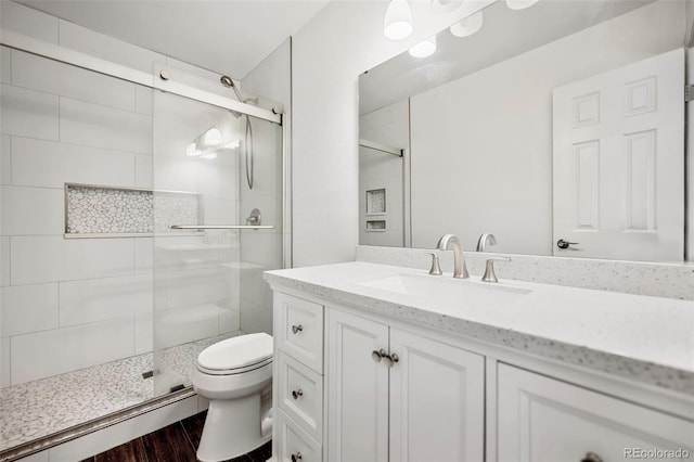 bathroom featuring vanity, toilet, a shower with shower door, and hardwood / wood-style floors