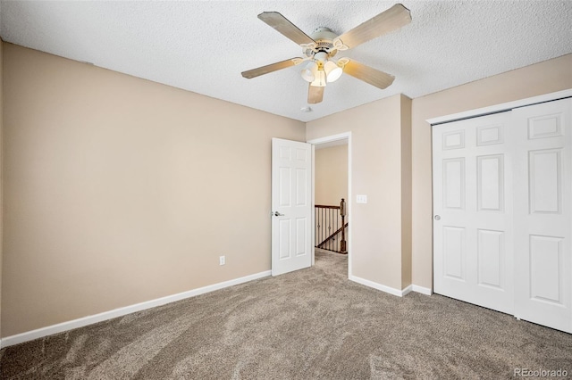 unfurnished bedroom featuring ceiling fan, a closet, a textured ceiling, and carpet flooring