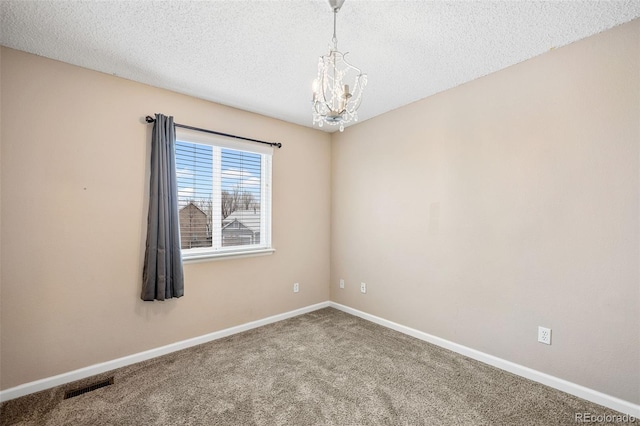 empty room featuring a textured ceiling, a chandelier, and carpet