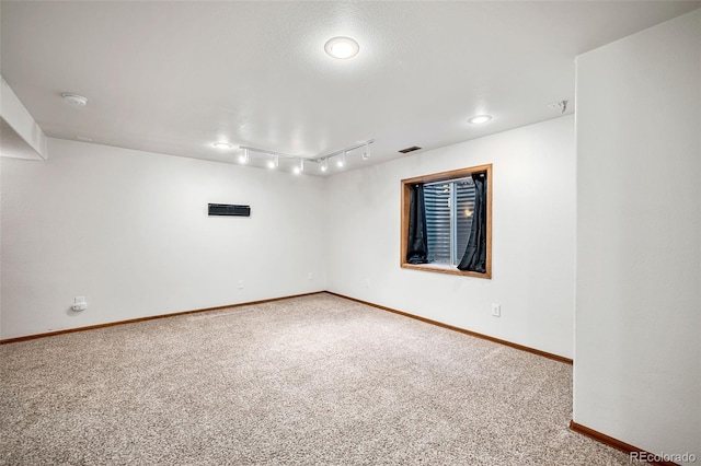 carpeted spare room featuring rail lighting