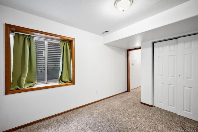 unfurnished bedroom featuring light carpet, a textured ceiling, and a closet