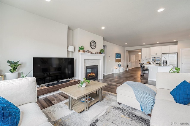living area featuring recessed lighting, a glass covered fireplace, and wood finished floors