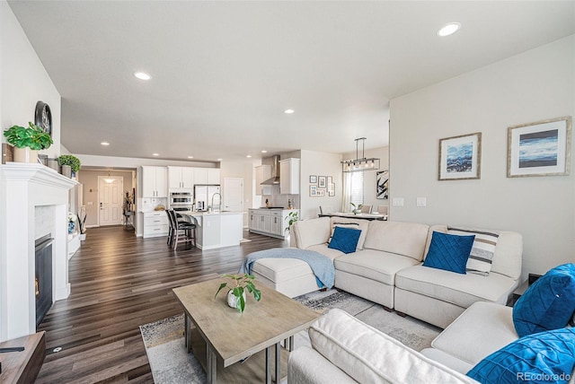 living area with a chandelier, dark wood-style floors, a glass covered fireplace, and recessed lighting