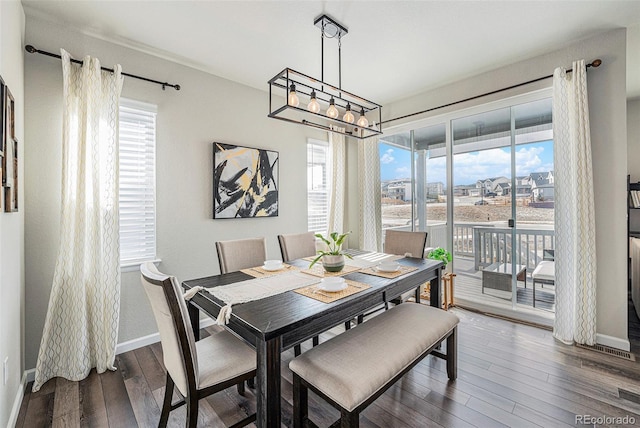 dining space with a chandelier, hardwood / wood-style flooring, and baseboards
