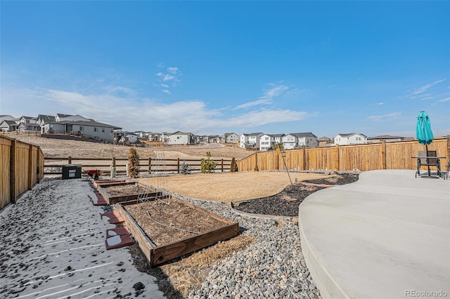 view of yard featuring a garden, a fenced backyard, and a residential view