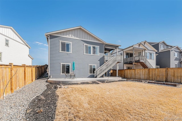back of house with a patio area, a lawn, board and batten siding, a fenced backyard, and a residential view