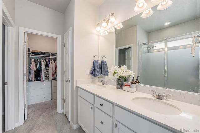 bathroom featuring a stall shower, double vanity, a sink, and a spacious closet