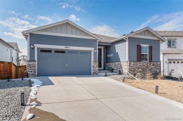 view of front of home featuring driveway, board and batten siding, stone siding, a garage, and fence