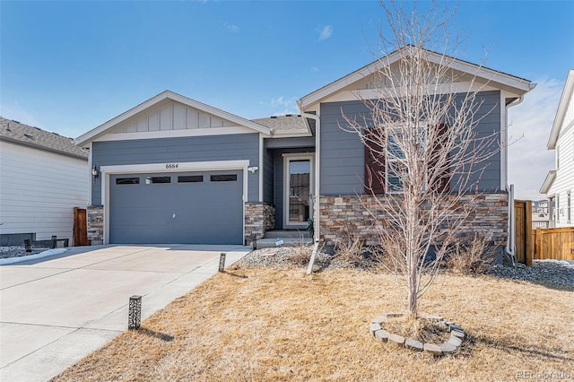 view of front of house with concrete driveway, stone siding, board and batten siding, an attached garage, and fence