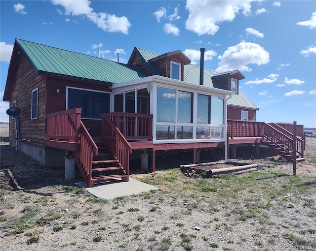 rear view of property featuring a sunroom and a wooden deck