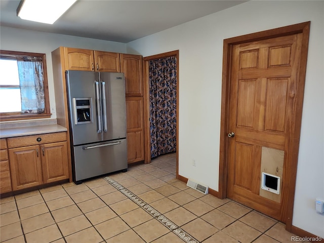 kitchen featuring stainless steel fridge and light tile floors