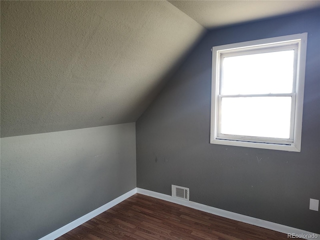 bonus room with a wealth of natural light, vaulted ceiling, a textured ceiling, and dark hardwood / wood-style floors