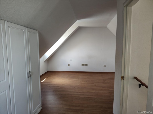 bonus room with a textured ceiling, dark hardwood / wood-style floors, and vaulted ceiling