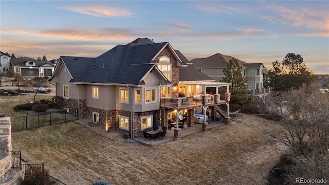 back of house at dusk featuring stairway, a wooden deck, a fenced backyard, stucco siding, and a patio area