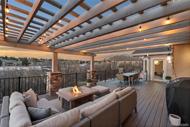 wooden deck with grilling area, an outdoor living space with a fire pit, outdoor dining space, and a pergola