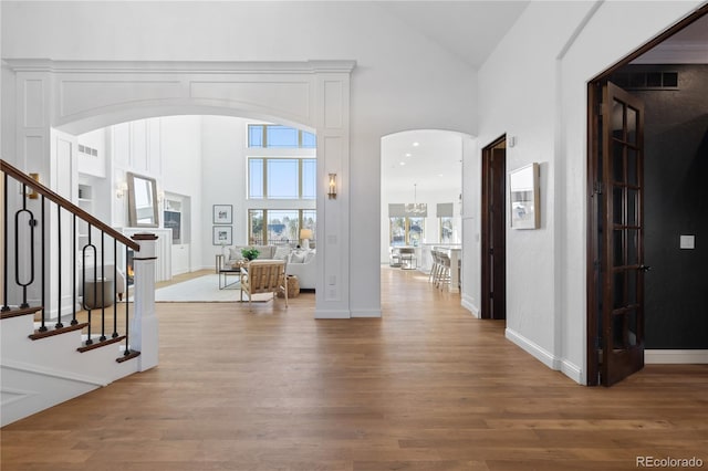 entryway with stairway, high vaulted ceiling, visible vents, and wood finished floors