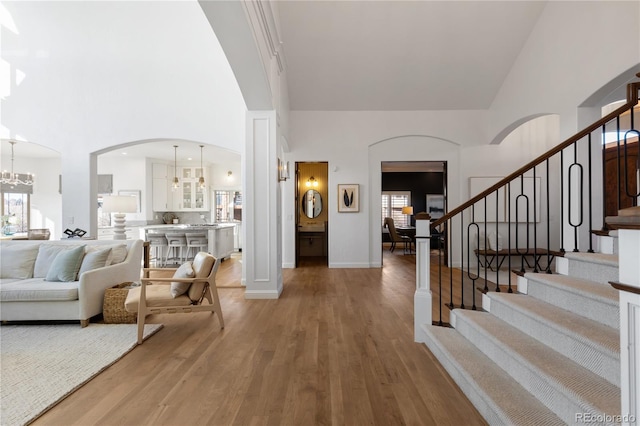 foyer entrance featuring stairway, arched walkways, a notable chandelier, and light wood-style flooring