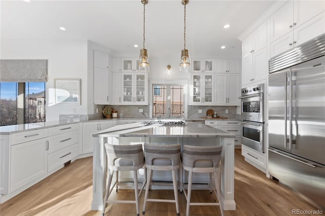 kitchen featuring tasteful backsplash, white cabinetry, stainless steel appliances, and light wood-type flooring