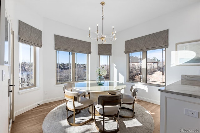 dining space featuring baseboards, light wood finished floors, and a chandelier