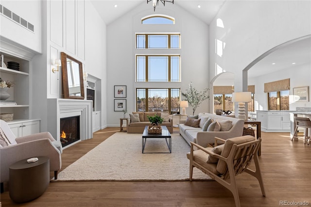 living area with arched walkways, visible vents, plenty of natural light, and wood finished floors