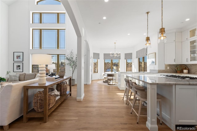 interior space with a wealth of natural light, glass insert cabinets, arched walkways, and a breakfast bar area