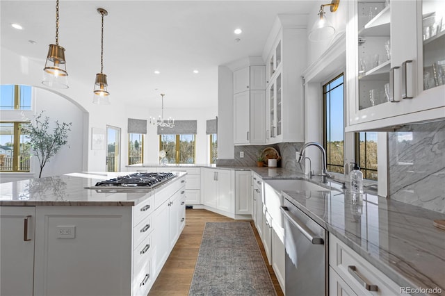 kitchen with tasteful backsplash, a center island, light stone countertops, wood finished floors, and stainless steel appliances