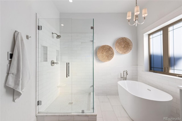 bathroom with a soaking tub, a shower stall, tile patterned floors, a notable chandelier, and tile walls