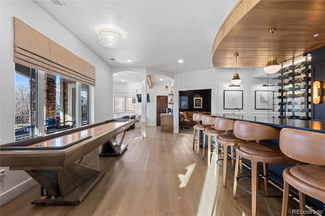 dining space with visible vents, a dry bar, arched walkways, and light wood-type flooring