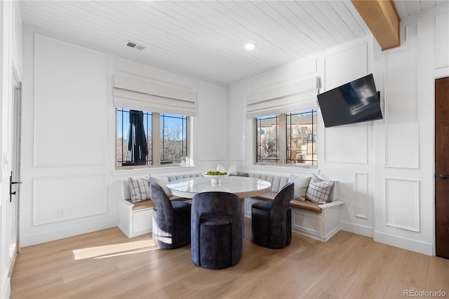 dining area with beam ceiling, a decorative wall, and breakfast area