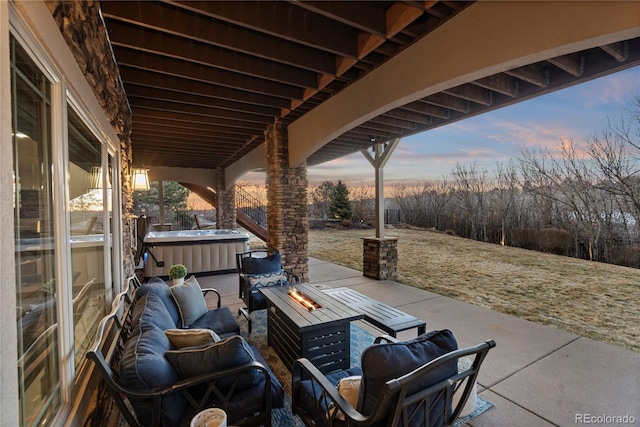 patio terrace at dusk featuring a hot tub and an outdoor fire pit