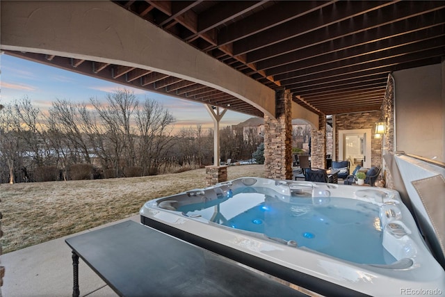 patio terrace at dusk featuring a hot tub