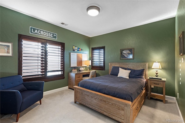 carpeted bedroom featuring visible vents, baseboards, and a textured wall